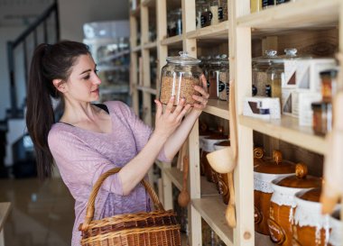 Yeniden kullanılabilir konteynırlar kullanarak kadın müşteri alışverişi yapıyor. Paketsiz mallar ve sürdürülebilir alternatifler sunan sıfır atık mağazası.