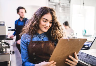 Kahve dükkanında tezgahta bekleyen iki genç barmen. Üniversite öğrencileri bir kafede yarı zamanlı çalışıyorlar..