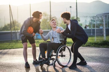 Tekerlekli sandalyede arkadaşlarıyla oyun alanında basketbol oynayan engelli bir genç. Takım ve erkek arkadaşlığı..