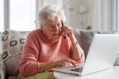 Üst düzey bir kadın dizüstü bilgisayarla çalışıyor, internetten alışveriş yapıyor, arama yapıyor. Yaşlılar için dijital okur yazarlığın önemi.