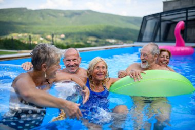 Bir grup neşeli son sınıf öğrencisi havuzda zıplayarak, yüzerek ve şamandıralarda uzanarak eğleniyor. Yaşlı arkadaşlar sıcak bir günü yüzme havuzunda geçiriyorlar..