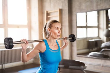 Bir kadın halteri yerden kaldırıyor. Fiziksel ve zihinsel sağlık için rutin çalışma