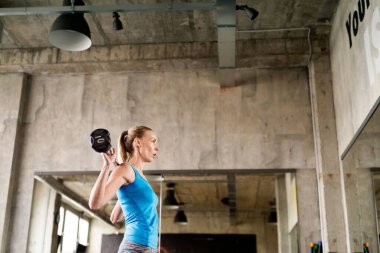 Bir kadın halteri yerden kaldırıyor. Fiziksel ve zihinsel sağlık için rutin çalışma