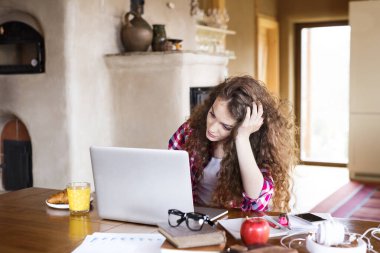 Güzel bir üniversite öğrencisi tezini dizüstü bilgisayarda yazıyor, evinde, kanepede oturuyor..