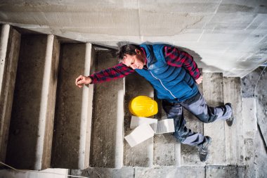 Erkek işçi düştükten sonra merdivenlerde yatıyor. İş kazası, iş yerinde kaza. İş kazası, iş yerinde kaza..