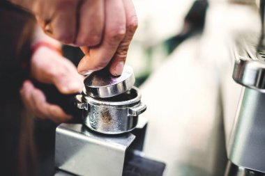 Kahve dükkanında çalışan baristanın ellerini kapat. Önlüklü barmen kahve hazırlıyor.