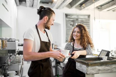 Kahve dükkanında tezgahta bekleyen iki genç barmen. Üniversite öğrencileri bir kafede yarı zamanlı çalışıyorlar..