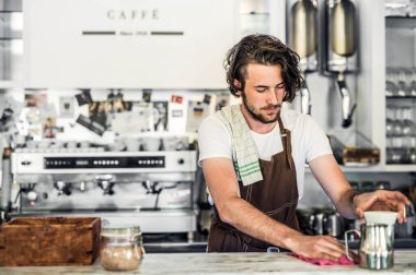 Kahve dükkanında çalışan yakışıklı barista, kahve hazırlıyor. Bir kafede yarı zamanlı çalışan üniversite öğrencisi..