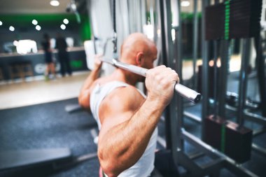 Spor salonunda egzersiz yapan güçlü bir adam. Fiziksel ve zihinsel sağlık için rutin egzersiz. Arka plan.