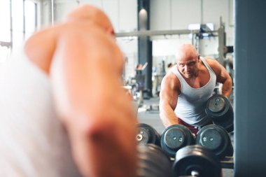 Adam halterden halteri seçiyor. Fiziksel ve zihinsel sağlık için rutin çalışma.