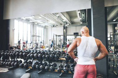 Adam halterden halteri seçiyor. Fiziksel ve zihinsel sağlık için rutin çalışma.