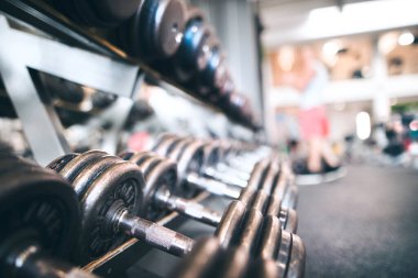 Spor salonunda dayanıklılık eğitimi için raflarda duran metal dambıllar.