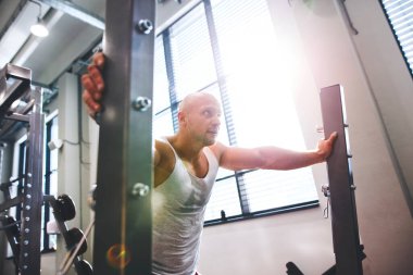 Spor salonunda egzersiz yapan güçlü bir adam. Dinleniyor. Fiziksel ve zihinsel sağlık için rutin çalışma.