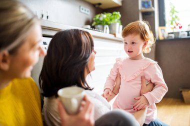 Anne, büyükanne ve küçük torun mutfakta, yerde oturuyor. Aile zamanı, ailede üç nesil kadın..