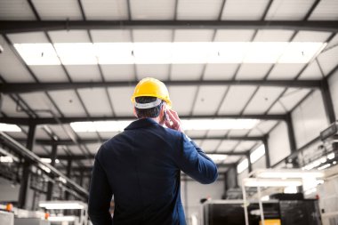 Modern endüstriyel fabrikada müdürün dikiz aynasından telefon görüşmesi yapması. Robot, robotik kollar ve otomasyon ile üretim tesisi.