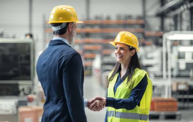 Warehouse worker shaking hand with logistics employee in warehouse, planning transport of products, goods, talking shipping process.Storing products and materials in warehouse. clipart