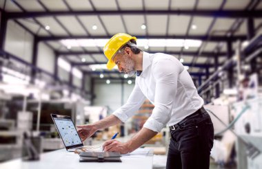 Modern endüstriyel fabrikada duran proje yöneticisinin portresi. Robot, robotik kollar ve otomasyon ile üretim tesisi.