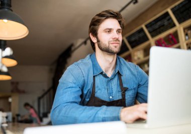 Küçük bir işi olan, bistrosunda çalışan, tedarikçisine e-posta yazan bir adam. Genç erkek işyeri sahibi..