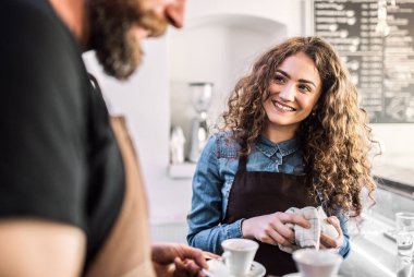 Kahve dükkanında çalışan iki genç barmen, tezgahta bekliyorlar..