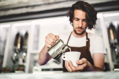 Kahve dükkanında çalışan yakışıklı barista, kahve hazırlıyor. Bir kafede yarı zamanlı çalışan üniversite öğrencisi..