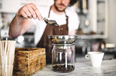 Kahve dükkanında çalışan yakışıklı barista, kahve hazırlıyor. Bir kafede yarı zamanlı çalışan üniversite öğrencisi..