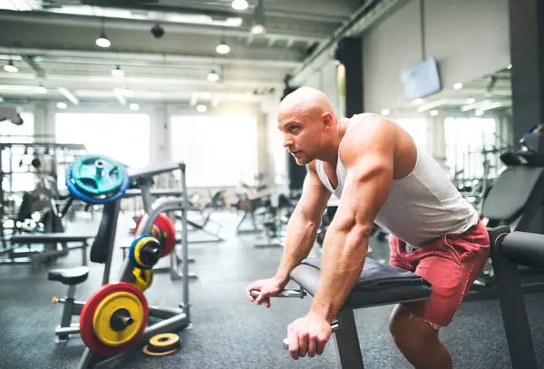 Spor salonunda egzersiz yapan güçlü bir adam. Dinleniyor. Fiziksel ve zihinsel sağlık için rutin çalışma.