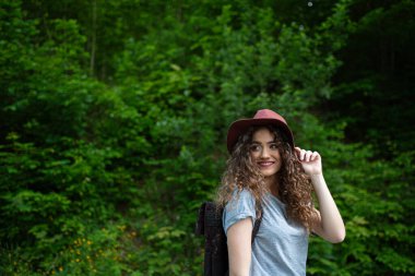 Sırt çantalı güzel bir turist kadın gezgin doğa yürüyüşü yapıyor. Ormanda yürüyüş yapan aktif bir kadın. Tek başına yaz tatili.