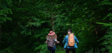 Gezgin çift doğada elektronik bisiklete biniyor. Ormanın ortasında yol kenarında elektrikli bisiklet süren bir turist. Genç turist romantik bir yaz tatilini dışarıda geçiriyor..