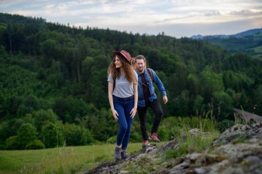 Gezgin çiftler sırt çantalarıyla kolay yoldan doğa yürüyüşü yapıyorlar. Genç turist romantik bir yaz tatilini dışarıda geçiriyor..