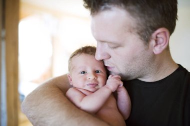 Baba yeni doğmuş bebeğini kucağında tutuyor. Koşulsuz baba sevgisi ve Babalar Günü konsepti.