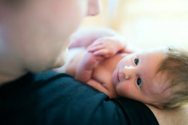 Baba yeni doğmuş bebeğini kucağında tutuyor. Koşulsuz baba sevgisi ve Babalar Günü konsepti.
