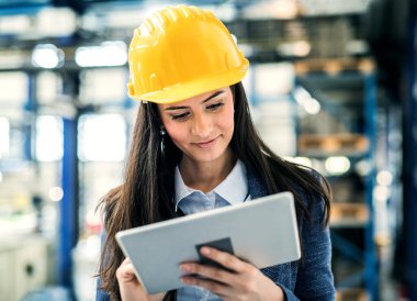 Modern endüstriyel fabrikada duran kadın proje yöneticisinin portresi. Robot, robotik kollar ve otomasyon ile üretim tesisi.