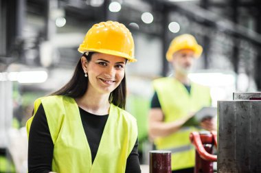 Depo çalışanları depoda. Modern endüstriyel fabrikada yansıtıcı giysiler içinde iki işçi, ağır sanayi.