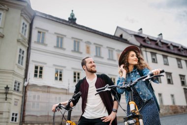 Elektrikli scooterlı bir çift gezgin, şehir turu. Yaz tatillerinde bisiklet kullanan genç turistler..