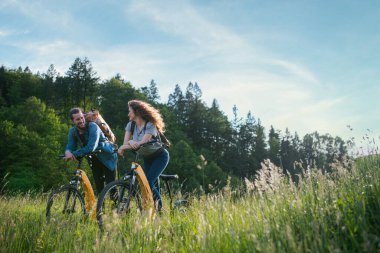 Gezgin çift doğada elektronik bisiklete biniyor. Ormanın ortasında yol kenarında elektrikli bisiklet süren bir turist. Genç turist romantik bir yaz tatilini dışarıda geçiriyor..