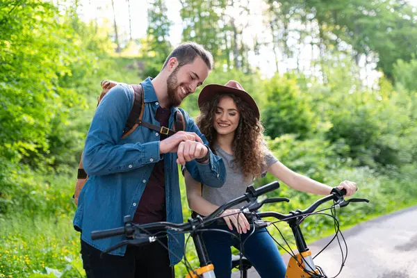 Gezgin çift doğada elektronik bisiklete biniyor. Ormanın ortasında yol kenarında elektrikli bisiklet süren bir turist. Genç turist romantik bir yaz tatilini dışarıda geçiriyor..