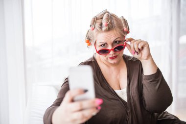 Güzel, genç, kilolu, aynaya bakıp eğlenen bir portre. Akıllı telefonla selfie çekiyordum. Güzellik ve vücut pozitifliği kavramı.