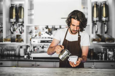 Kahve dükkanında çalışan yakışıklı barista, kahve hazırlıyor. Bir kafede yarı zamanlı çalışan üniversite öğrencisi..