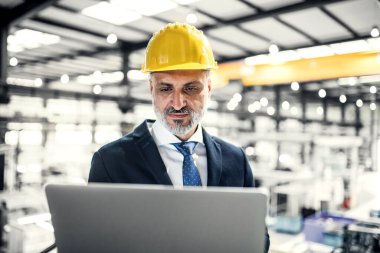 Modern endüstriyel fabrikada elinde tablet olan proje yöneticisinin portresi. Robot, robotik kollar ve otomasyon ile üretim tesisi.