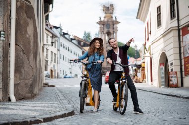 Elektrikli scooterlı bir çift gezgin, şehir turu. Yaz tatillerinde bisiklet kullanan genç turistler..