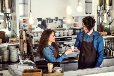 Kahve dükkanında tezgahta bekleyen iki genç barmen. Üniversite öğrencileri bir kafede yarı zamanlı çalışıyorlar..