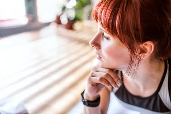 stock image Headshot of beautiful redhead woman during fitness routine. Home workout on gym mt in living room, sporty woman wearing sportswear clothes.