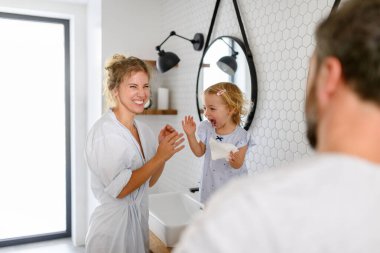 Ebeveynler ve kızları sabah banyosu rutini yapıyorlar. Dişleri fırçalamak, yüzünü yıkamak, evde birlikte vakit geçirmek..