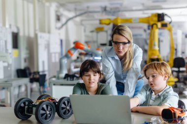 Children learning robotics in Elementary school. Young students programming, building robot in after school robotics club. Field trip to real robotics laboratory. clipart