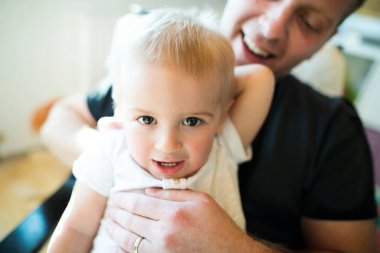 Baba oğlunu kucağında tutuyor, odasında bebekle vakit geçiriyor. Koşulsuz baba sevgisi ve Babalar Günü konsepti.