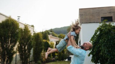 Baba küçük oğlunu bahçeye fırlatıyor. Babası ve çocuğu dışarıda eğleniyorlar. Babalar Günü konsepti.