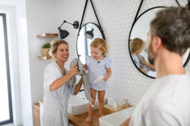 Ebeveynler ve kızları sabah banyosu rutini yapıyorlar. Dişleri fırçalamak, yüzünü yıkamak, evde birlikte vakit geçirmek..