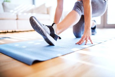 Kadınların spor salonu rutini. Bacaklarını kapat, spor salonundaki spor paspasın üzerinde çalış spor kıyafeti giyen bir kadın.