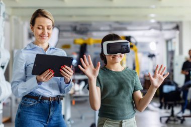 Liseli kız kafasında VR kulaklıkla öğreniyor. Öğretmen modern teknolojiyi kullanıyor, sınıfta sanal gerçeklik..
