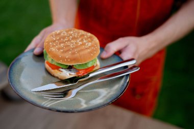 Ev yapımı ızgara hamburger ve çatal bıçaklı adam tabağı yakın..